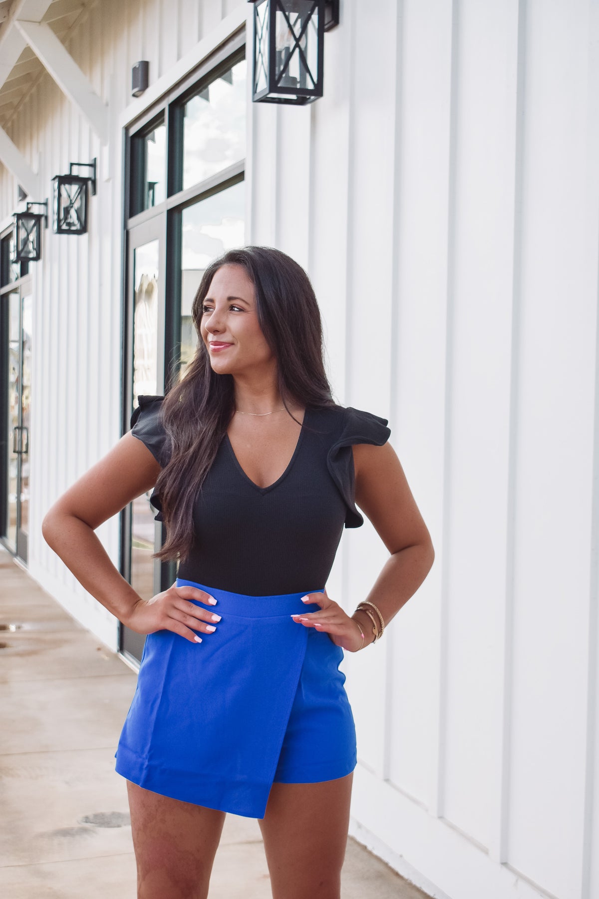 black bodysuit, featuring a ribbed knit material, v-neckline and a short ruffle sleeve.