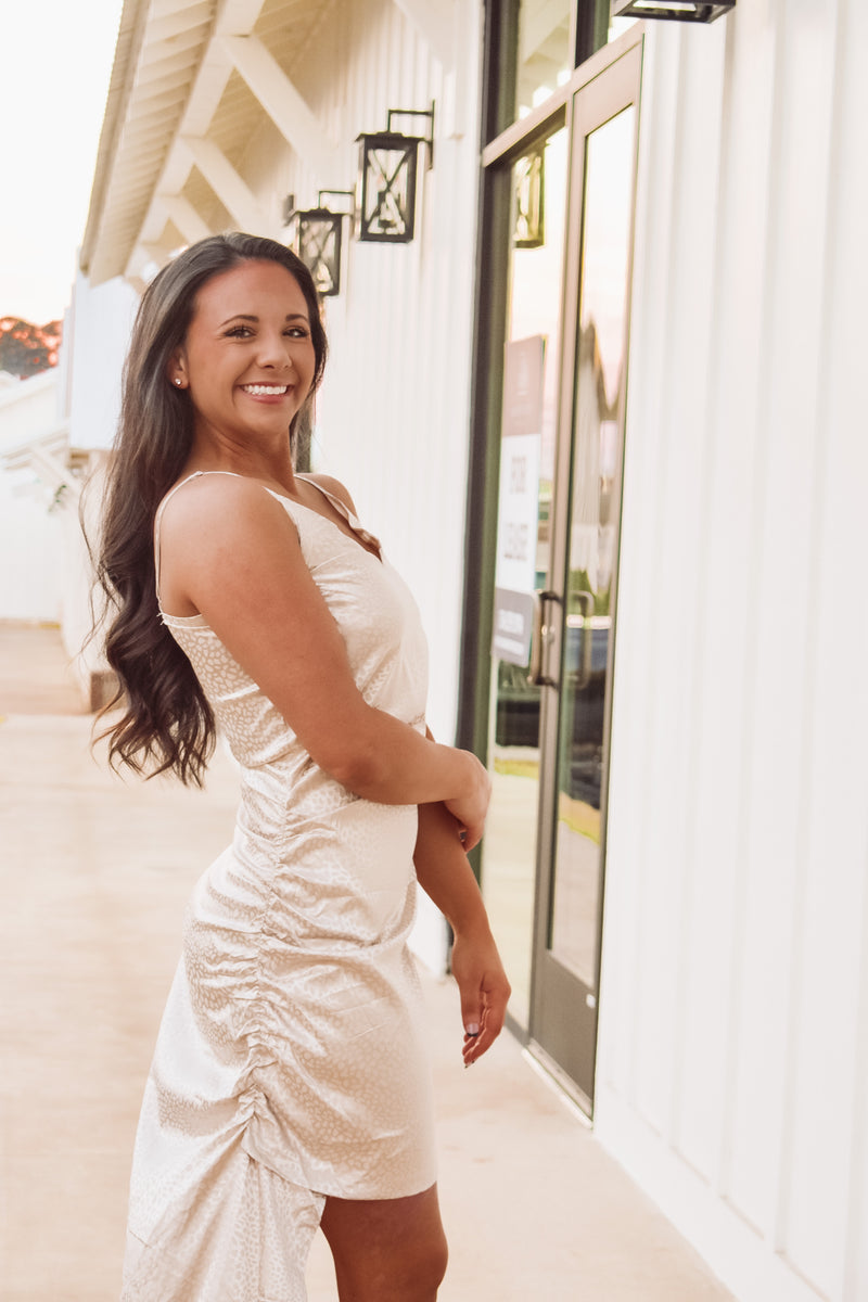 Gorgeous cream color asymmetric satin mini dress featuring adjustable spaghetti straps, cowl neckline, side slit along bottom hem, and back zipper closure!