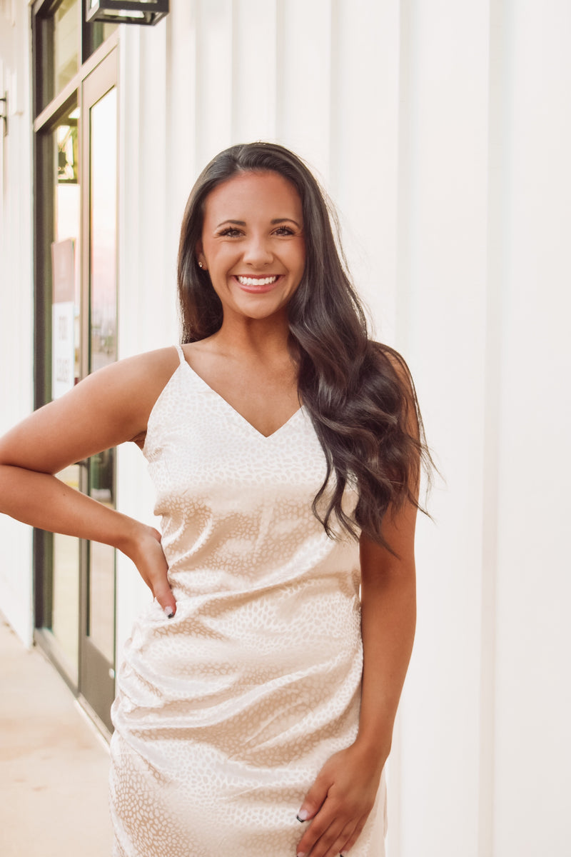 Gorgeous cream color asymmetric satin mini dress featuring adjustable spaghetti straps, cowl neckline, side slit along bottom hem, and back zipper closure!