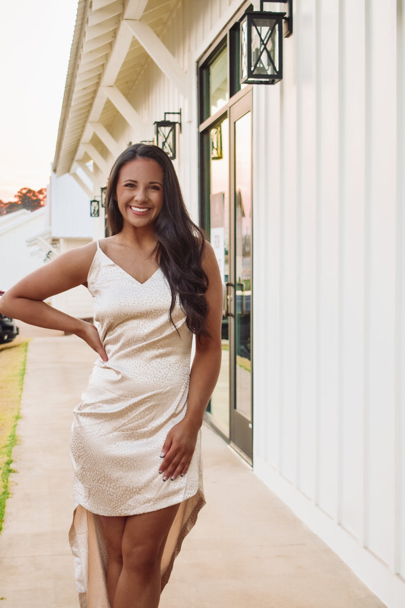 Gorgeous cream color asymmetric satin mini dress featuring adjustable spaghetti straps, cowl neckline, side slit along bottom hem, and back zipper closure!