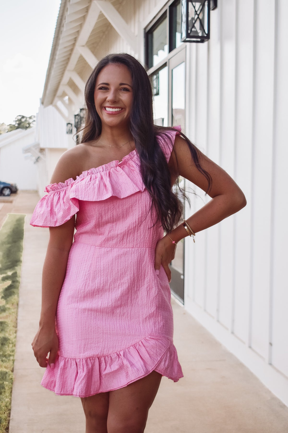 Gorgeous barbie pink asymmetrical dress,  featuring a textured fabric, ruffle accent along the neckline and tulip styled hem. 